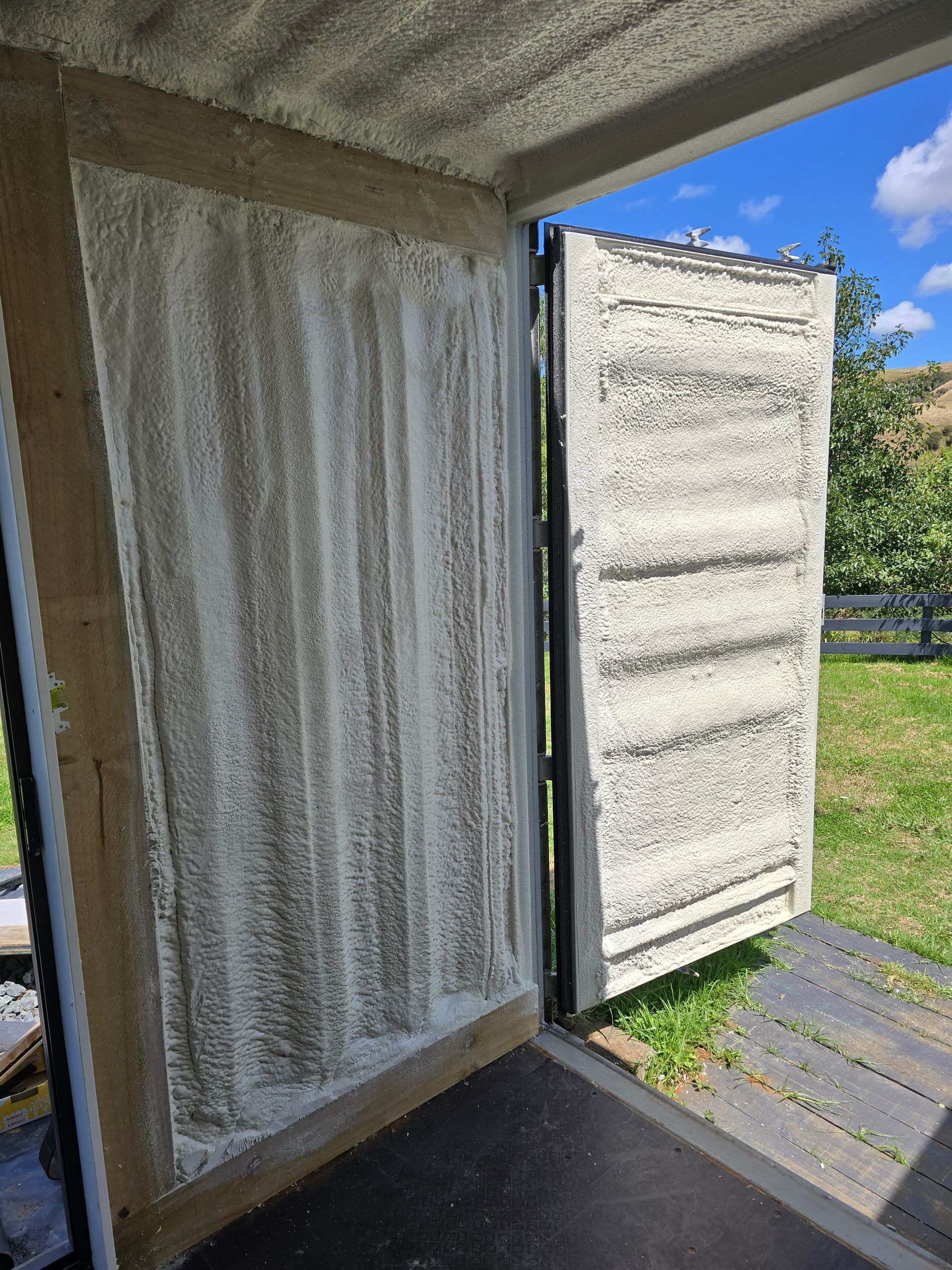 A door with a lot of foam on it is open to a field.