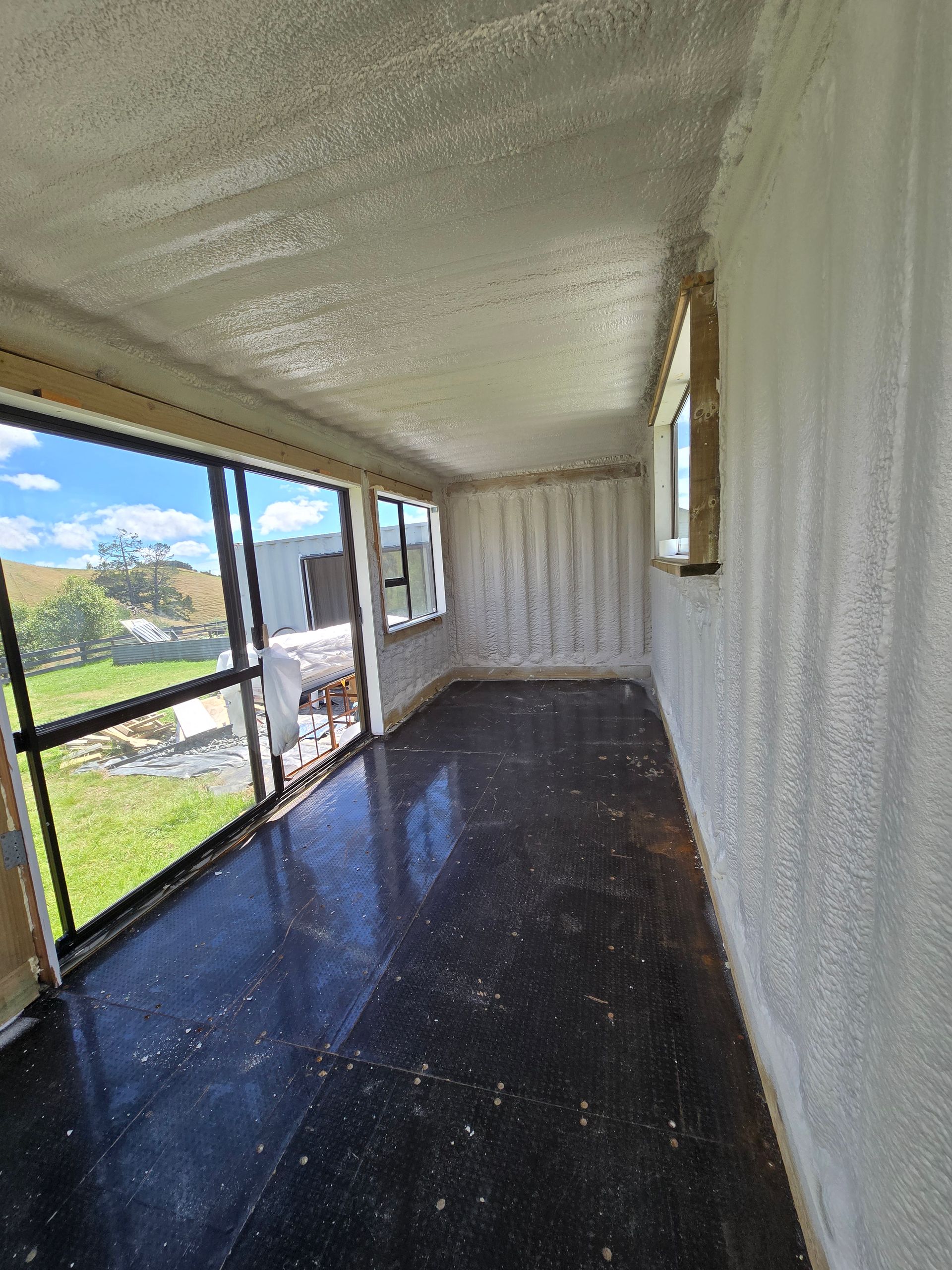 A room with a lot of windows and a black floor.