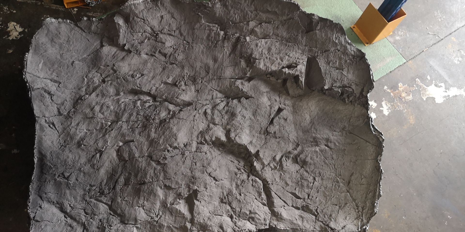 A pile of concrete is sitting on the floor next to a shovel.