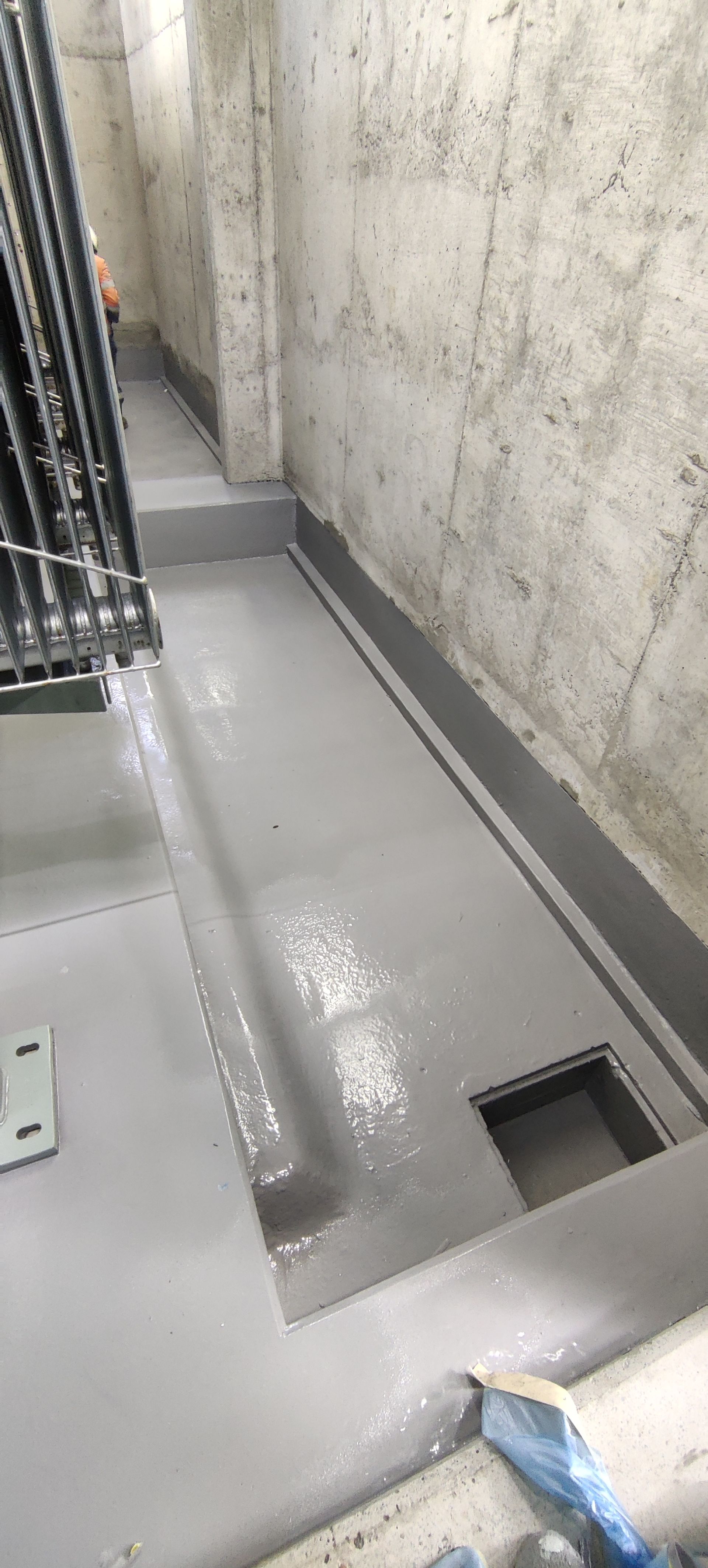 A room with a drain on the floor and a hole in the wall.