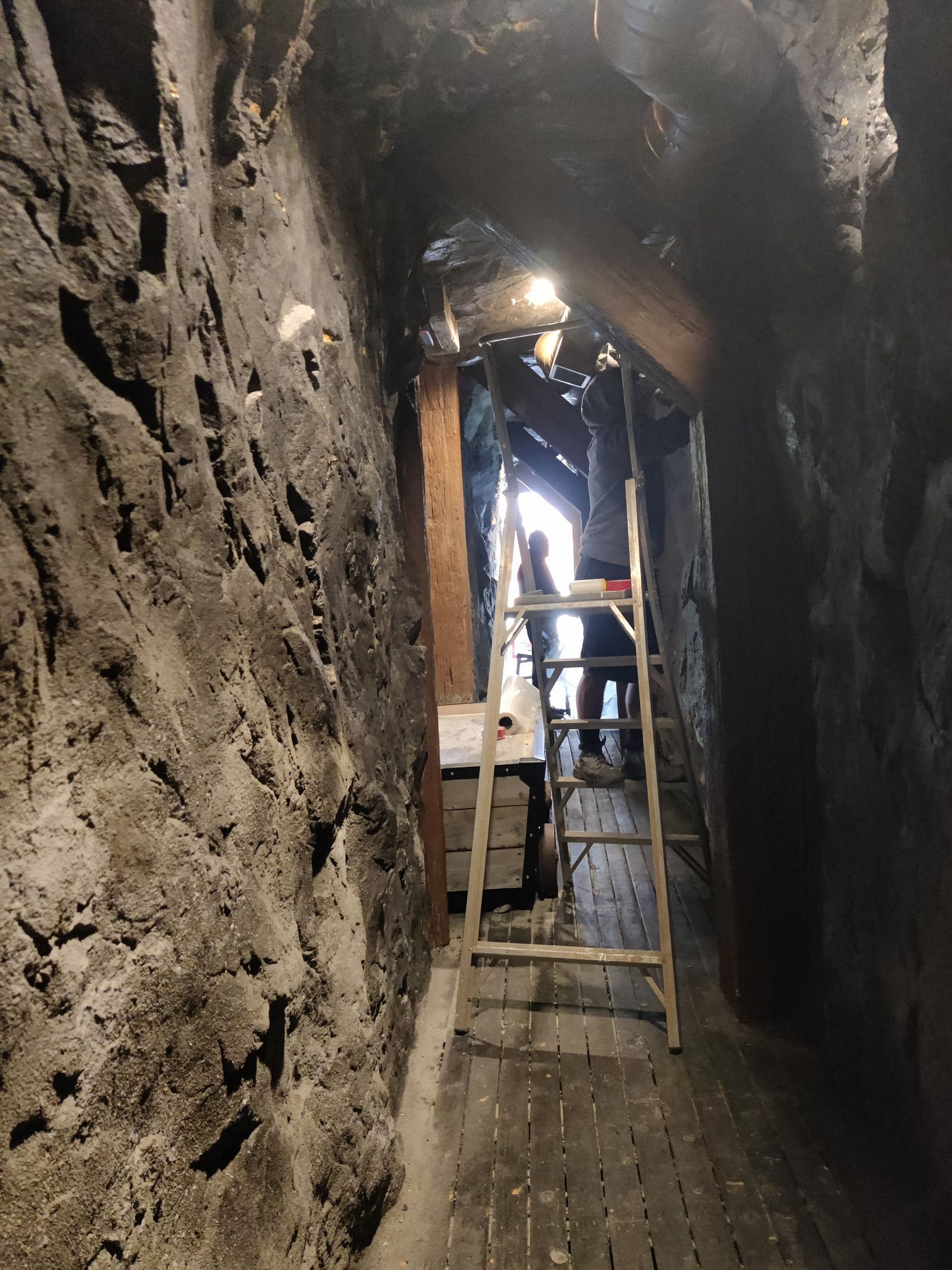 A man wearing a gas mask is spraying insulation on a wall.