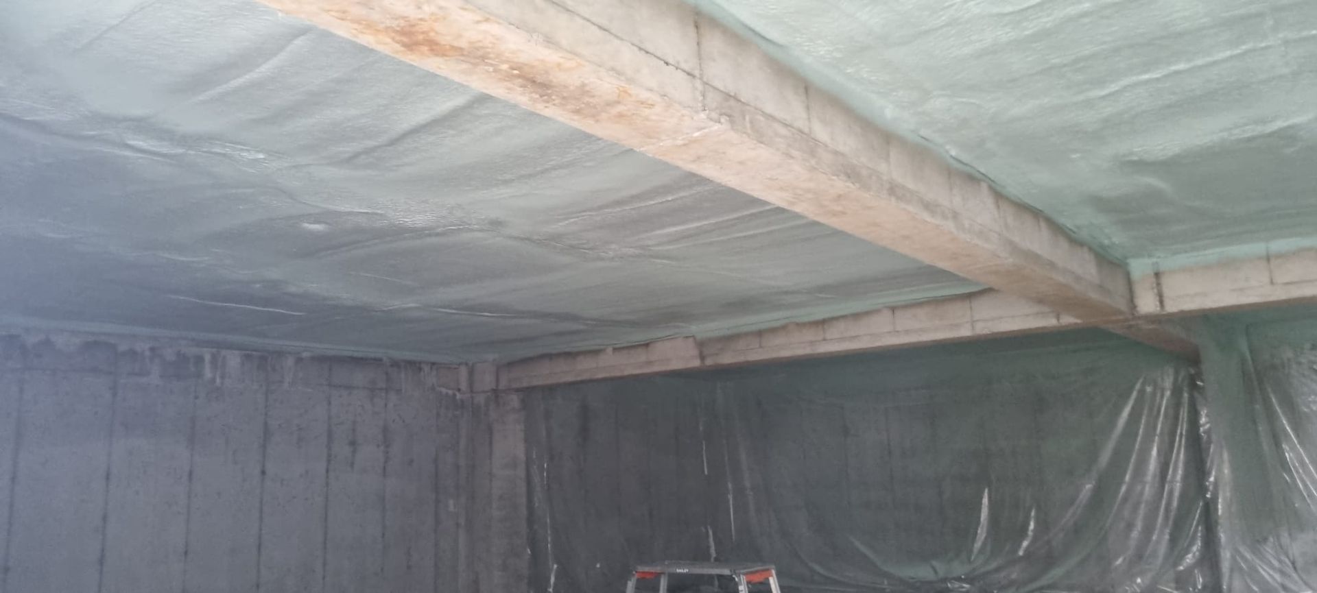 A room with a ladder in it and a ceiling that is covered in plastic.