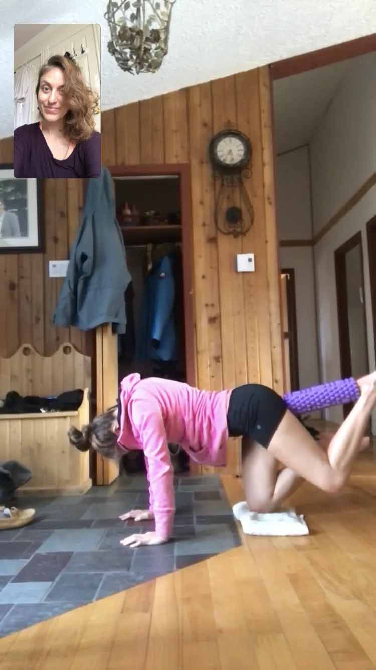 Une femme en chemise rose fait des exercices dans un salon