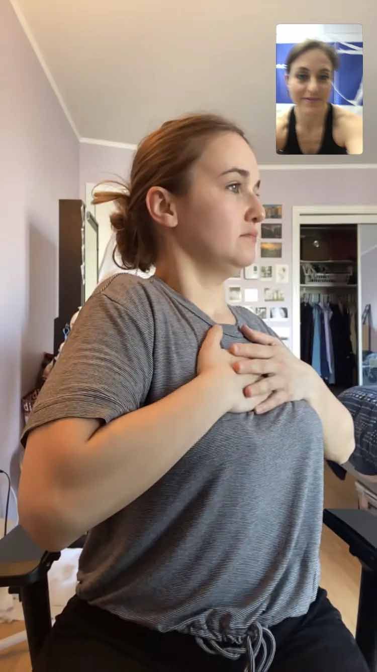 Une femme est assise sur une chaise avec ses mains sur sa poitrine.