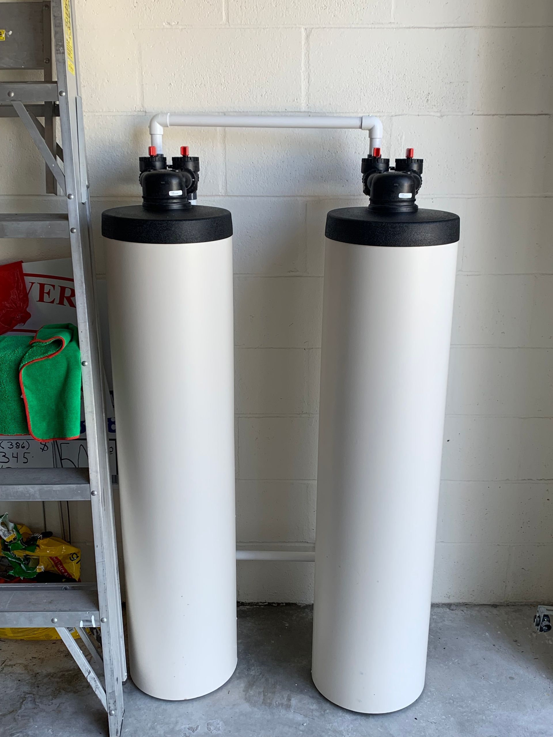 A faucet fills a clear glass with water over a stainless steel sink.