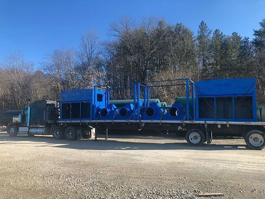 A blue semi truck is carrying a large blue pipe on a trailer