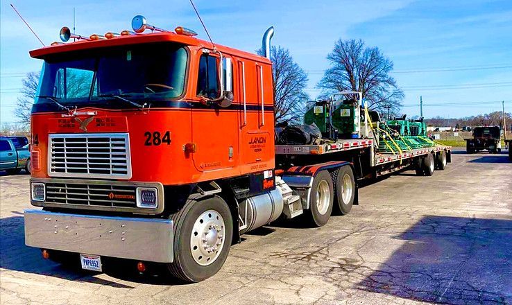 An orange semi truck with the number 284 on the side is parked in a parking lot.