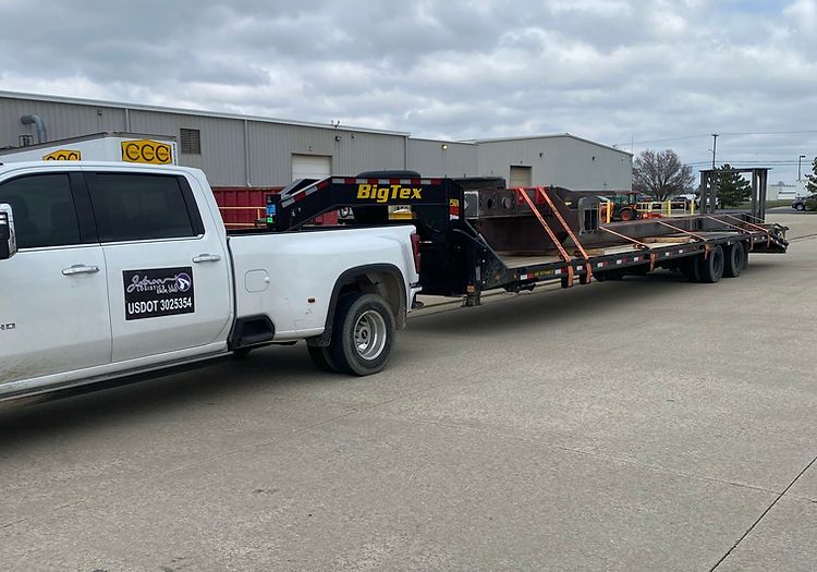 A white truck with a trailer attached to it is parked in a parking lot