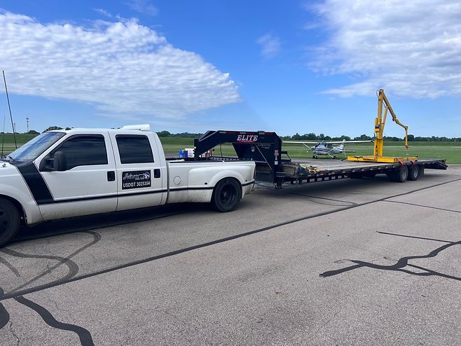 A white truck is towing a yellow trailer with a crane on it