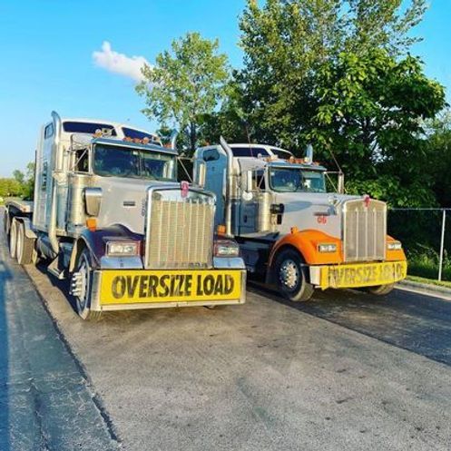 Two semi trucks are parked next to each other on the side of the road