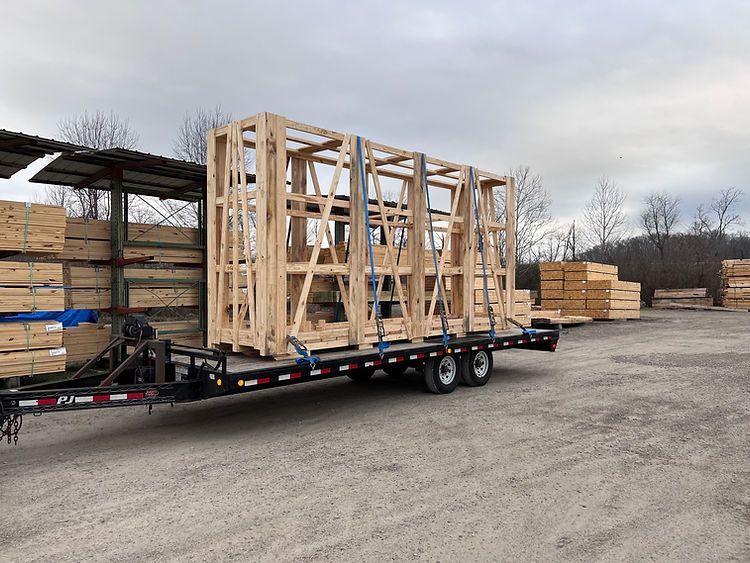 A trailer filled with wooden crates is parked in a dirt lot