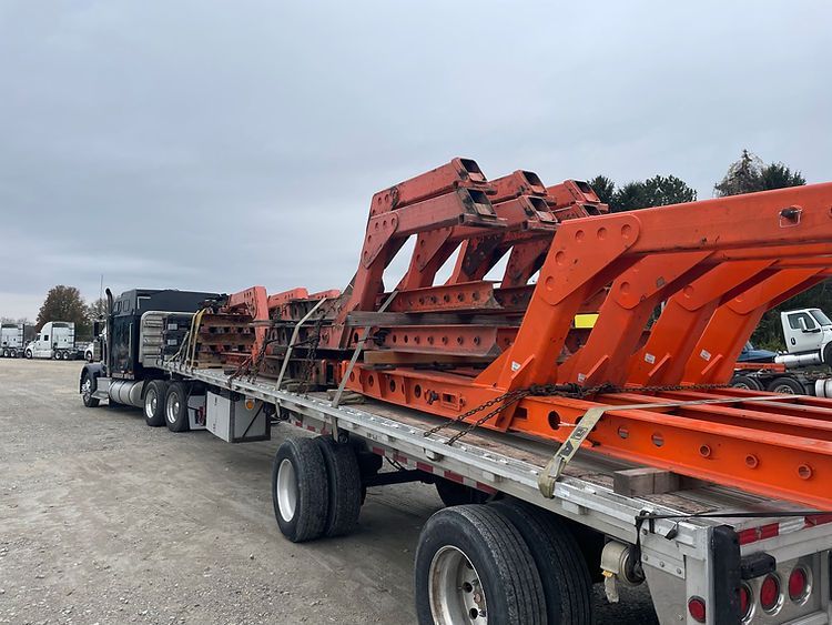 A semi truck is carrying a large piece of metal on a flatbed trailer