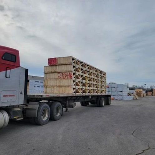 A semi truck is carrying a stack of wooden pallets