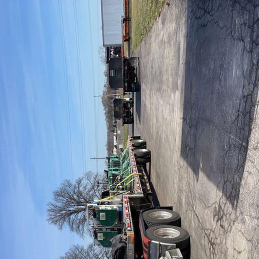 A semi truck is driving down a road with trees in the background
