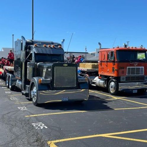 Two semi trucks are parked next to each other in a parking lot