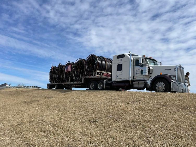 A white semi truck is parked on top of a grassy hill