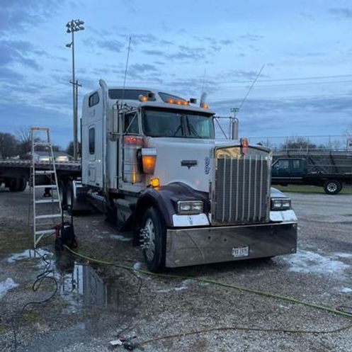 A semi truck is parked in a parking lot next to a ladder