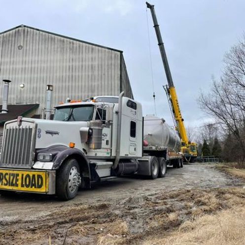 A semi-truck with a large load sign on the side is parked in front of a building