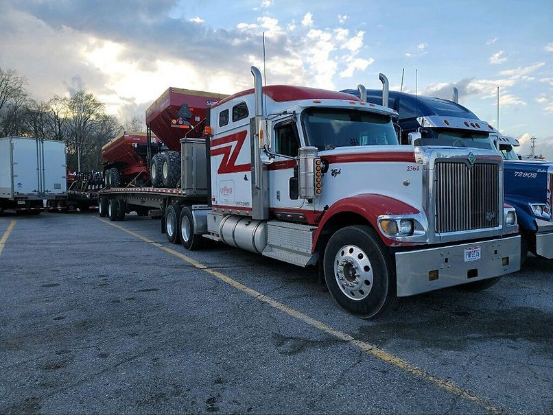 A red and white semi truck is parked in a parking lot