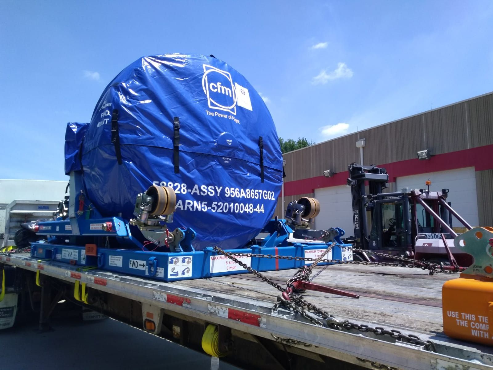 A large blue object is sitting on top of a flatbed truck