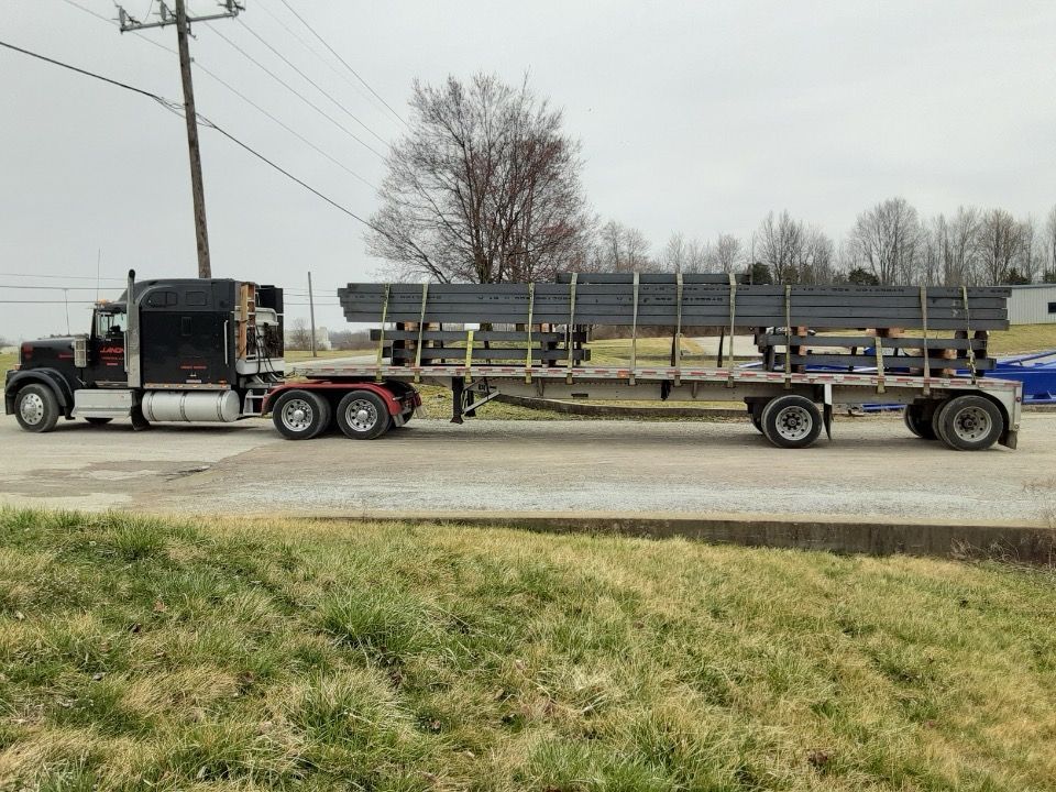 A semi truck is carrying a large load of steel beams on a trailer.