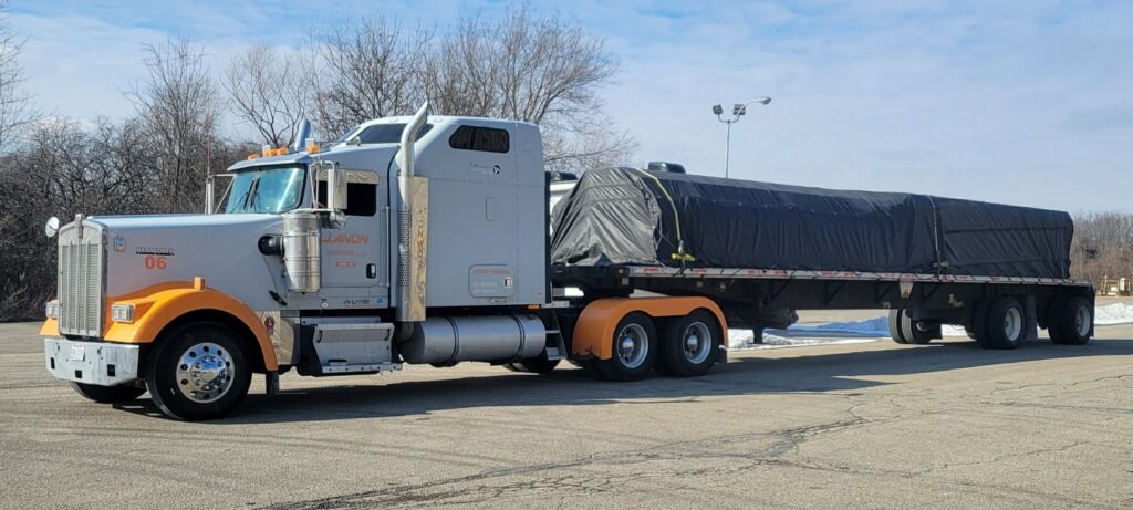 A semi truck with a trailer attached to it is parked in a parking lot.