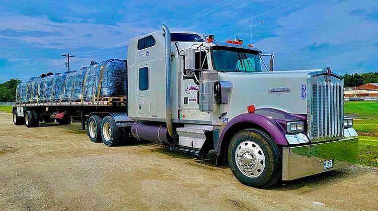 A semi truck is parked on the side of a dirt road.