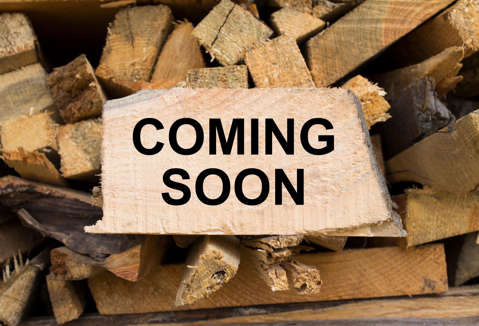 A wooden sign that says `` coming soon '' is sitting on top of a pile of wood.