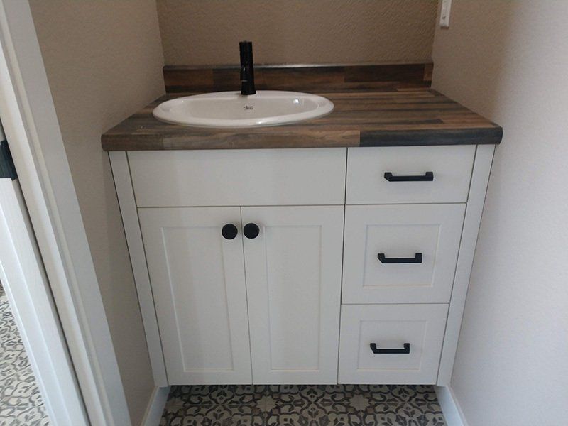 bathroom sink cabinet with brown wood countertop