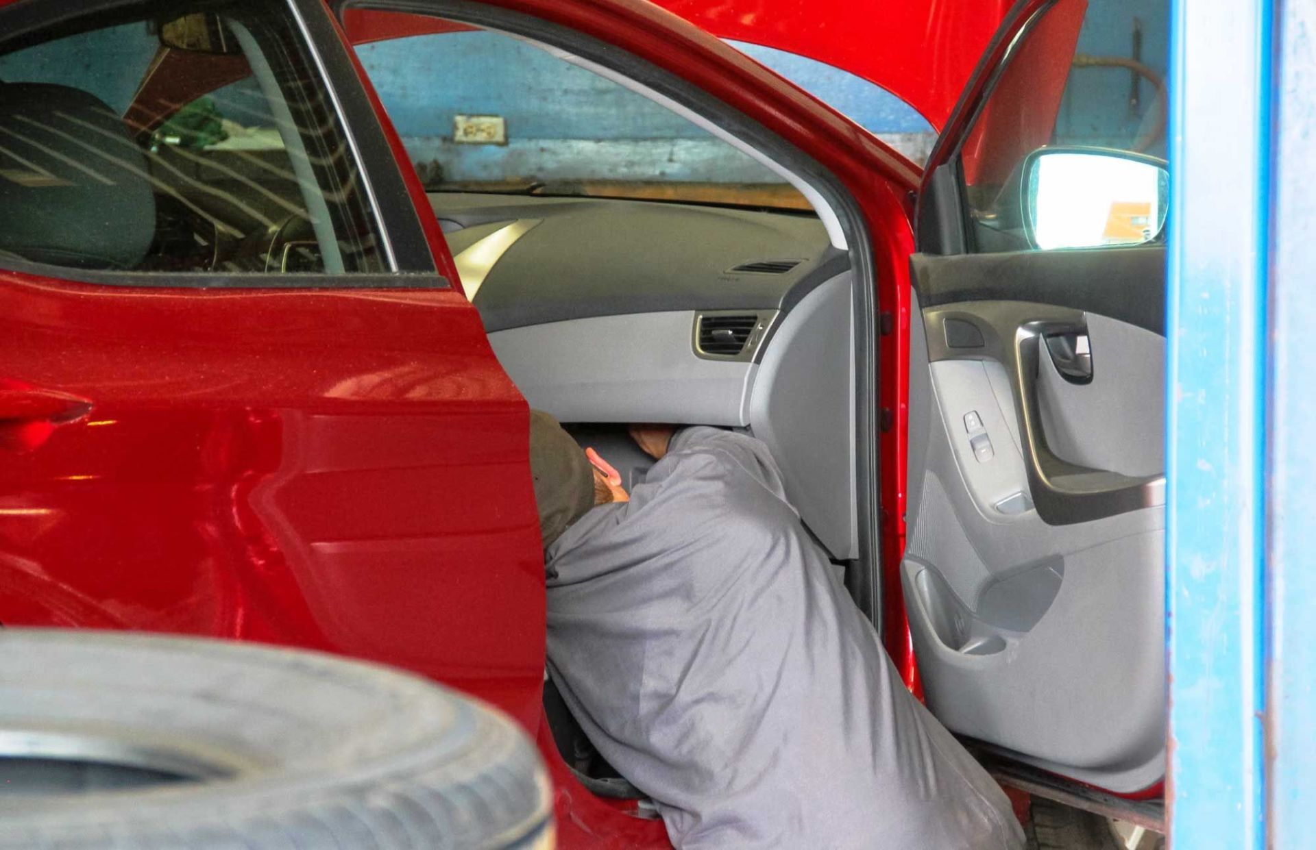 mechanic working on car wiring below front desk