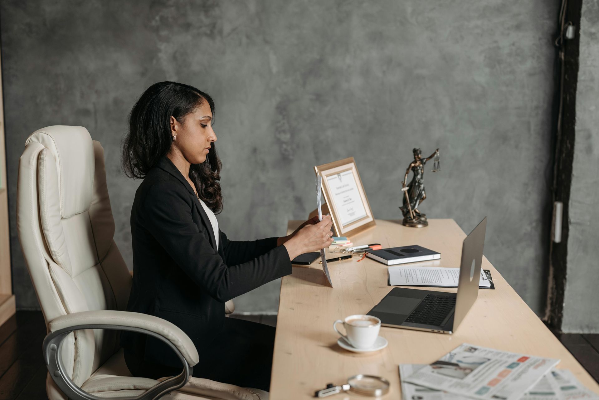 A woman is sitting on a couch talking on a cell phone while holding a piece of paper.