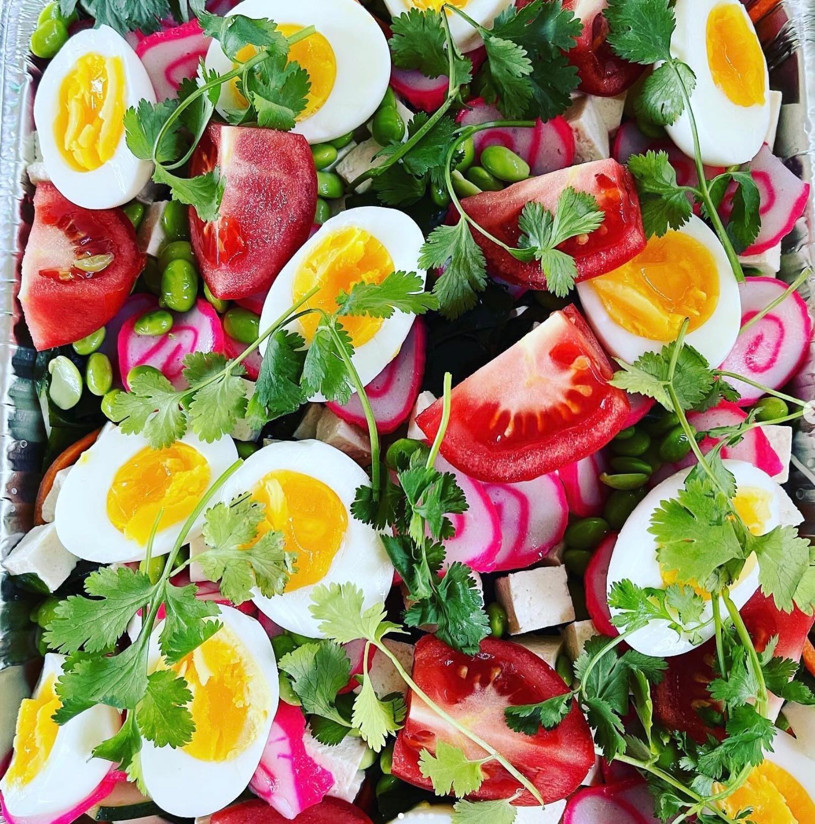 Colorful salad with boiled eggs, strawberries, radishes, cilantro, and greens