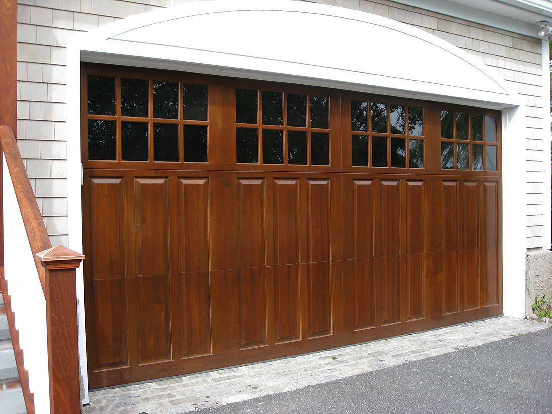 Wooden garage door with small windows set in a white brick building