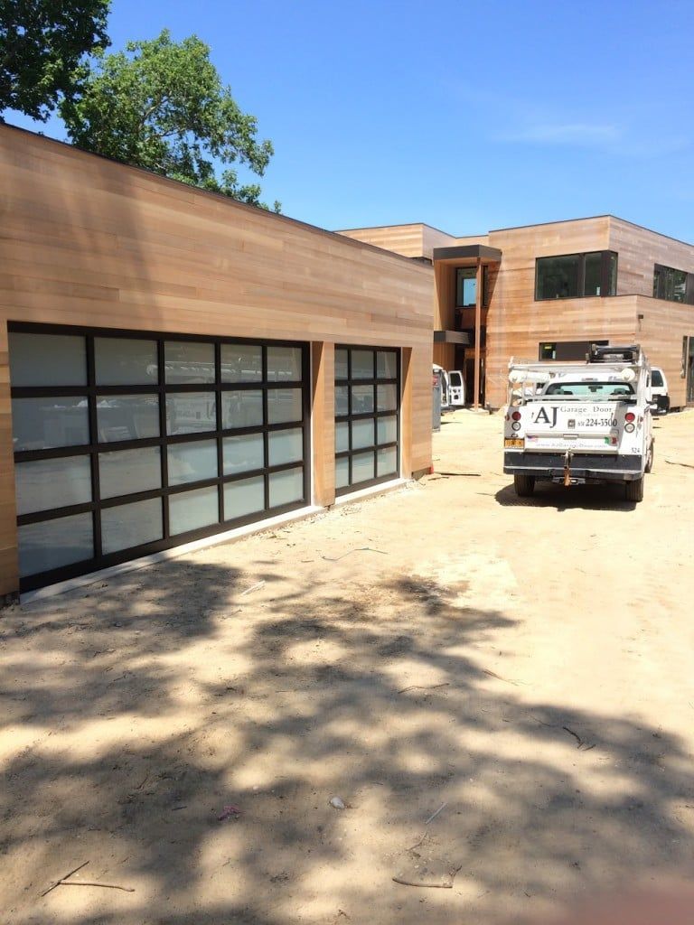 Modern building exterior with garage doors and a white utility truck in a sunny driveway