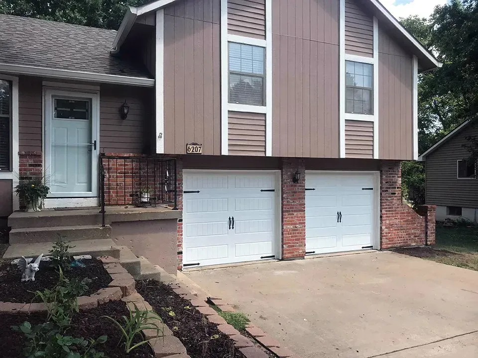 A house with two garage doors and a brick wall