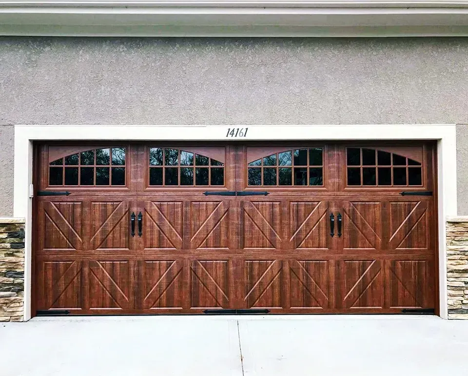 A large wooden garage door is on the side of a house.