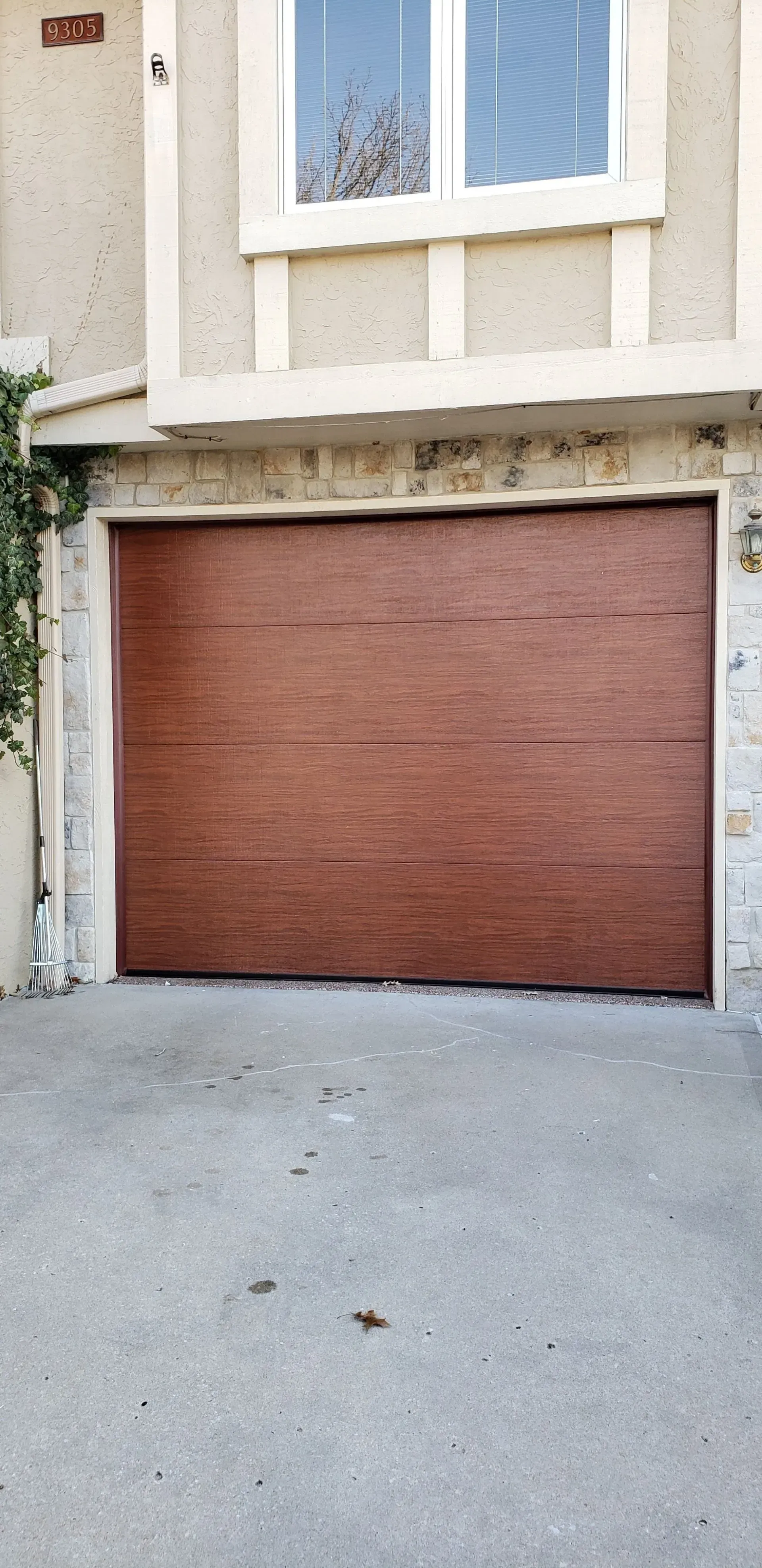 A red garage door is sitting in front of a building with a window.