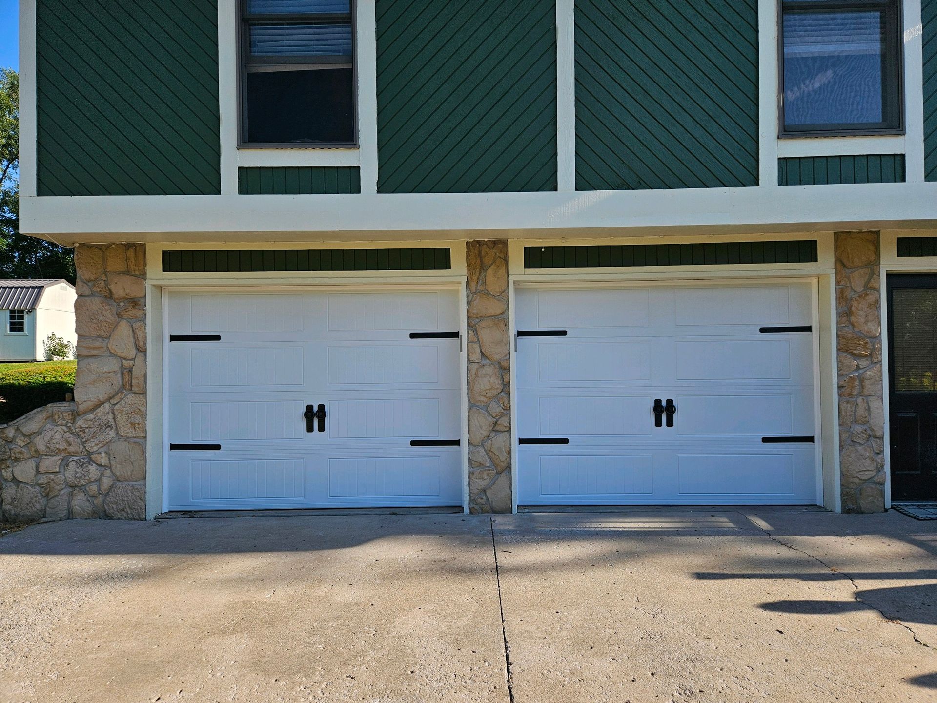 A green and white house with two white garage doors