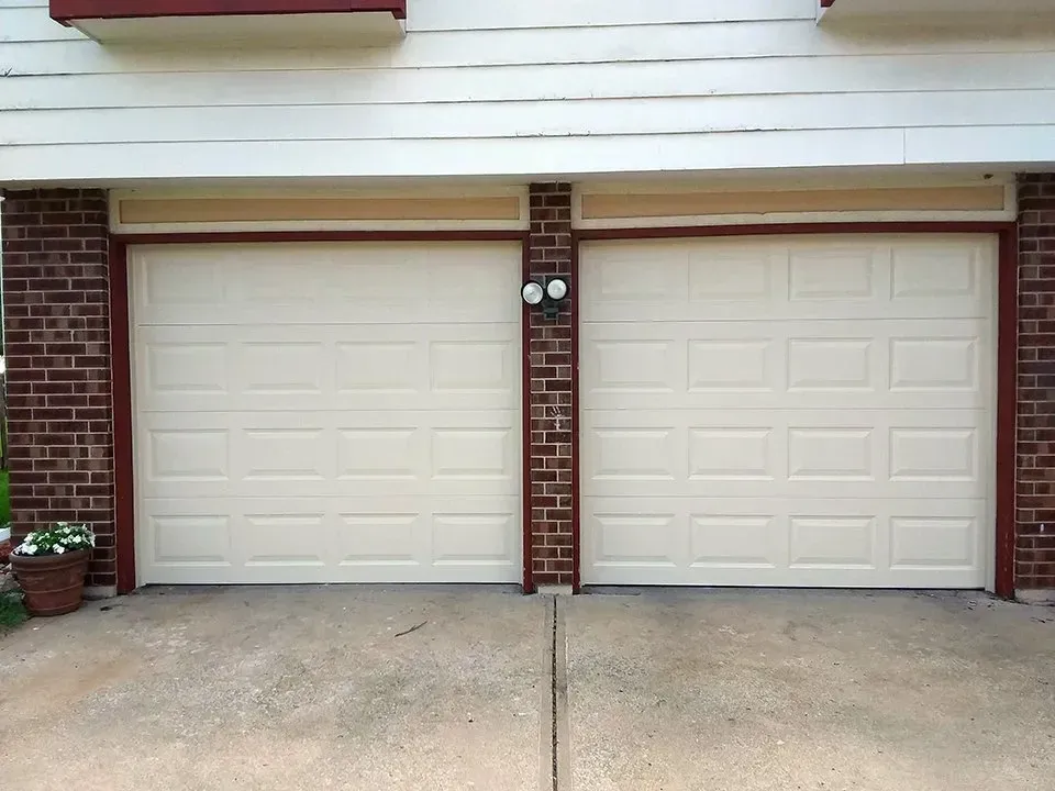Two white garage doors on a brick building
