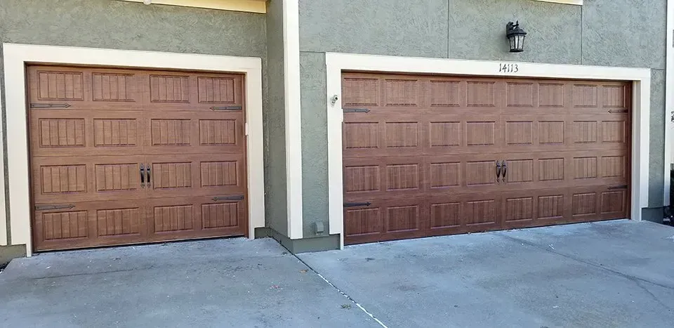 Two wooden garage doors are sitting next to each other on the side of a building.
