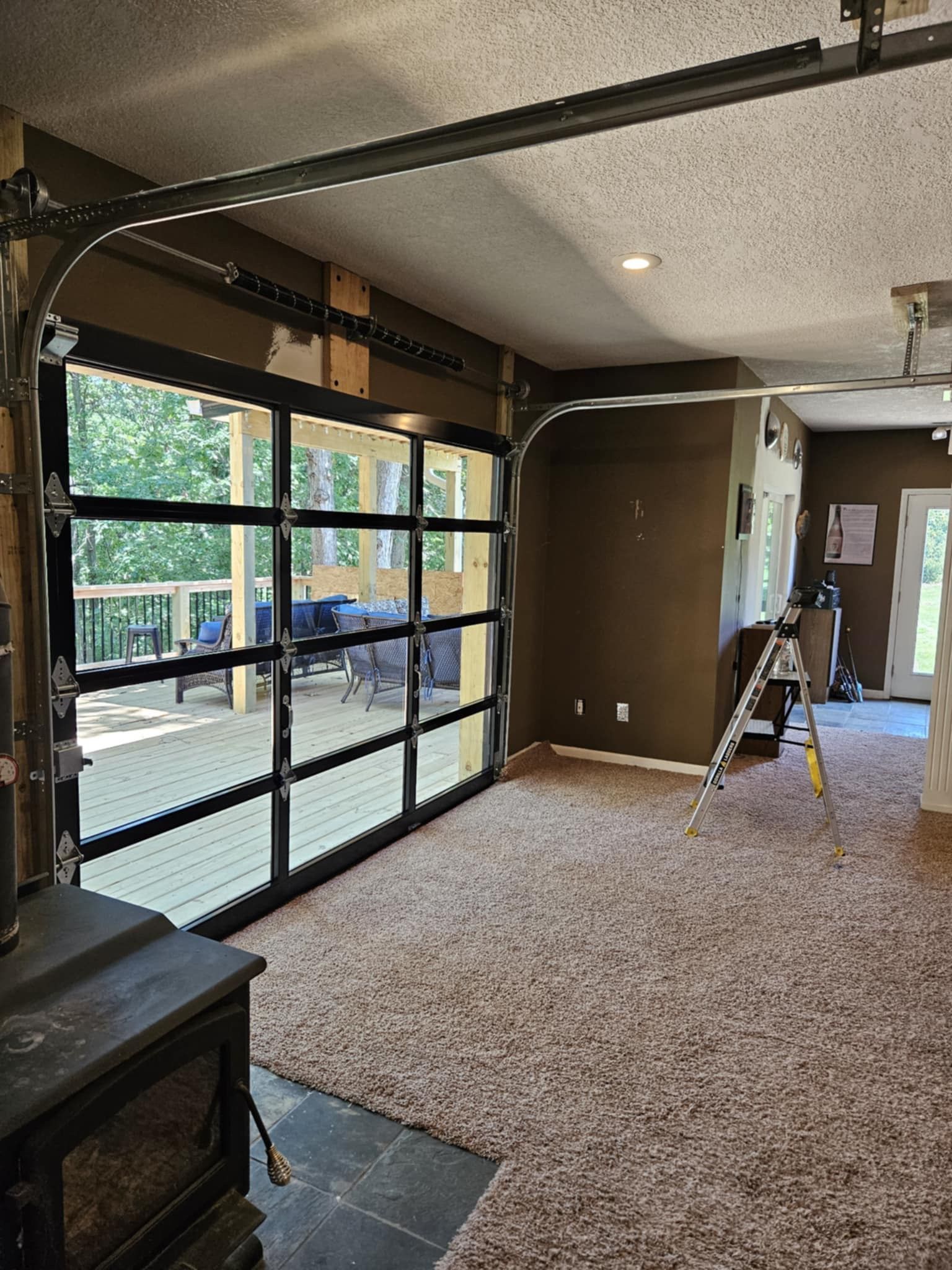 A garage door with a lot of windows is open in a living room.