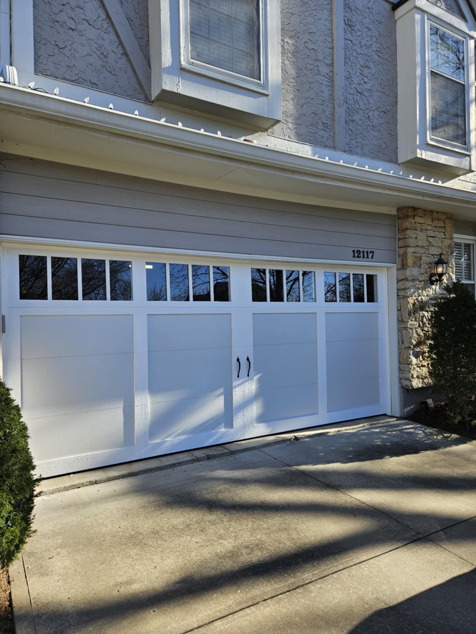 A white garage door is sitting in front of a house.
