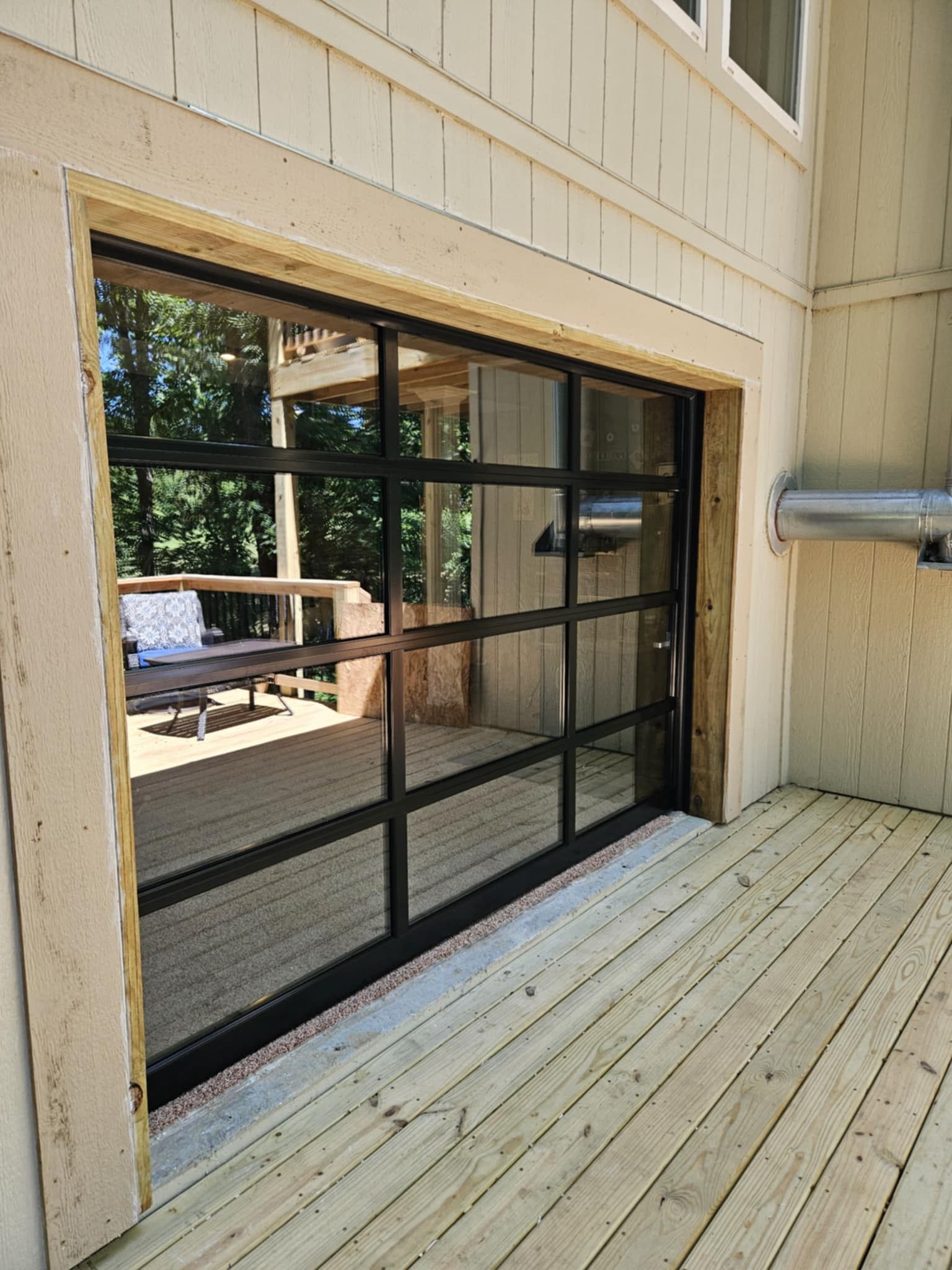 A sliding glass garage door is open to a wooden deck.