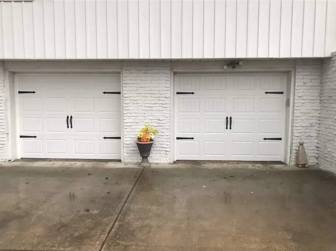 A white garage door with a potted plant in front of it.
