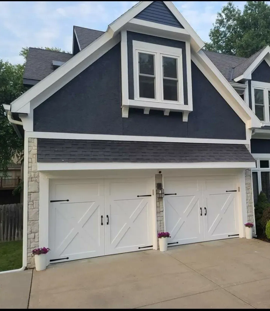 A blue house with white garage doors and a window