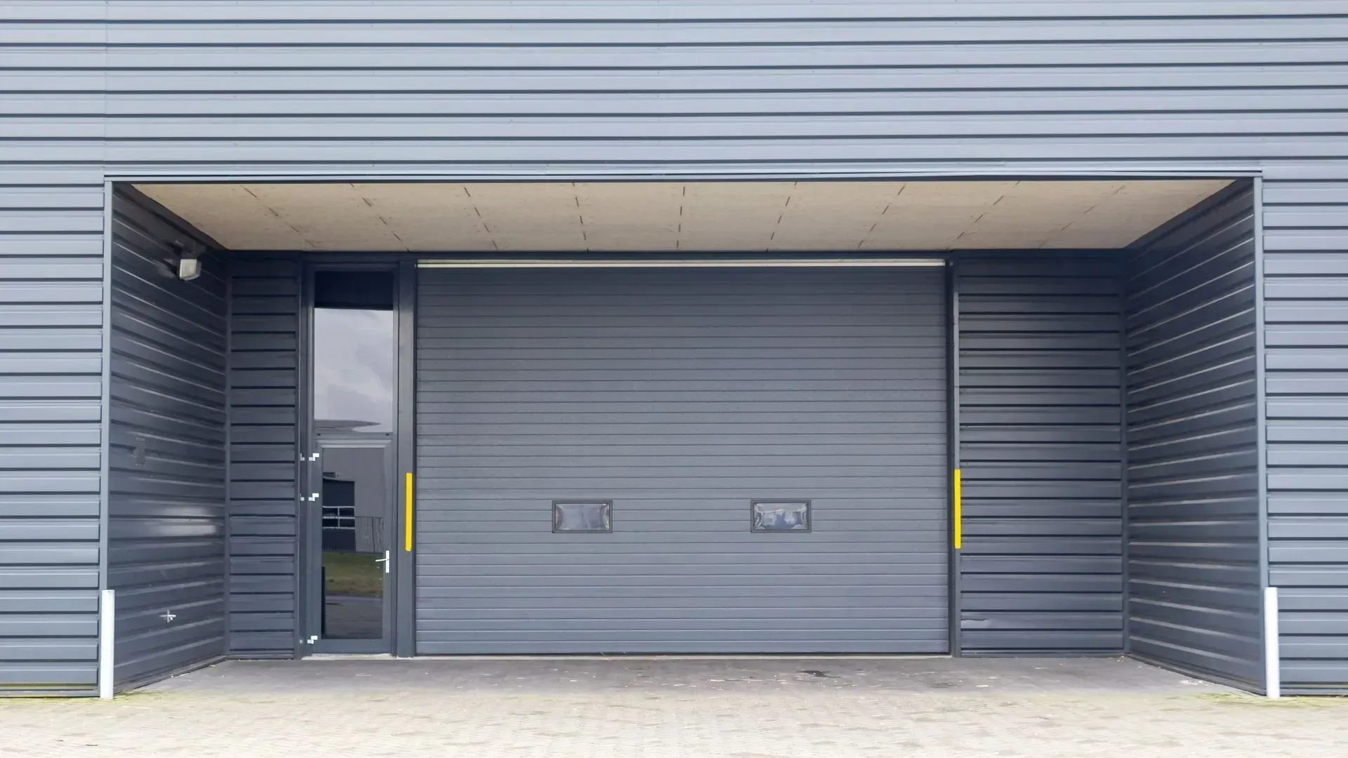 A large gray garage door is open in a building.