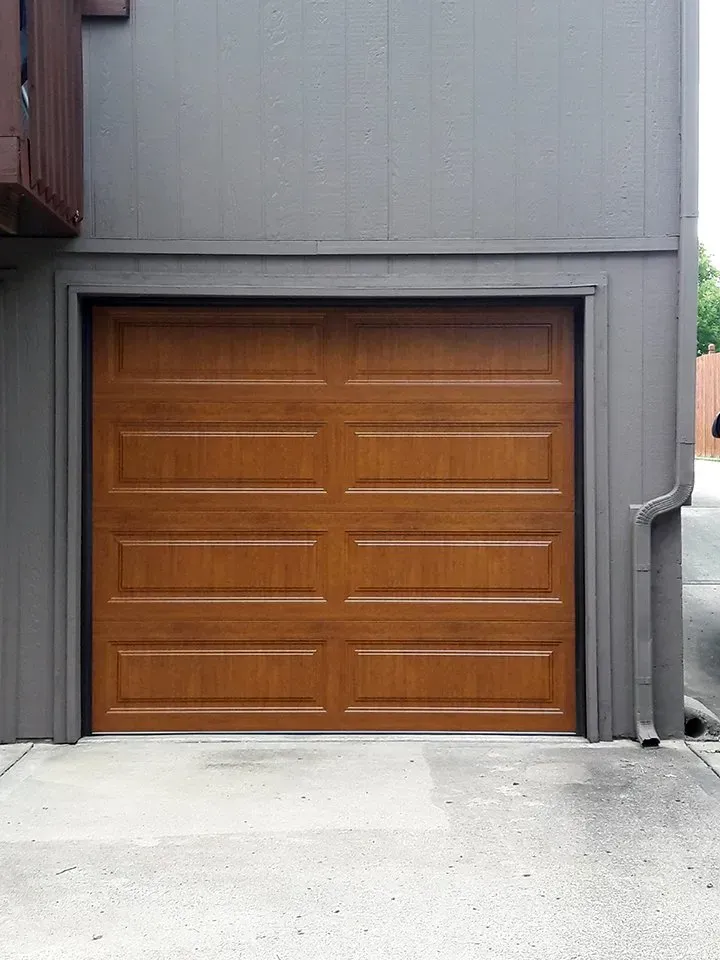 A wooden garage door is on the side of a building.