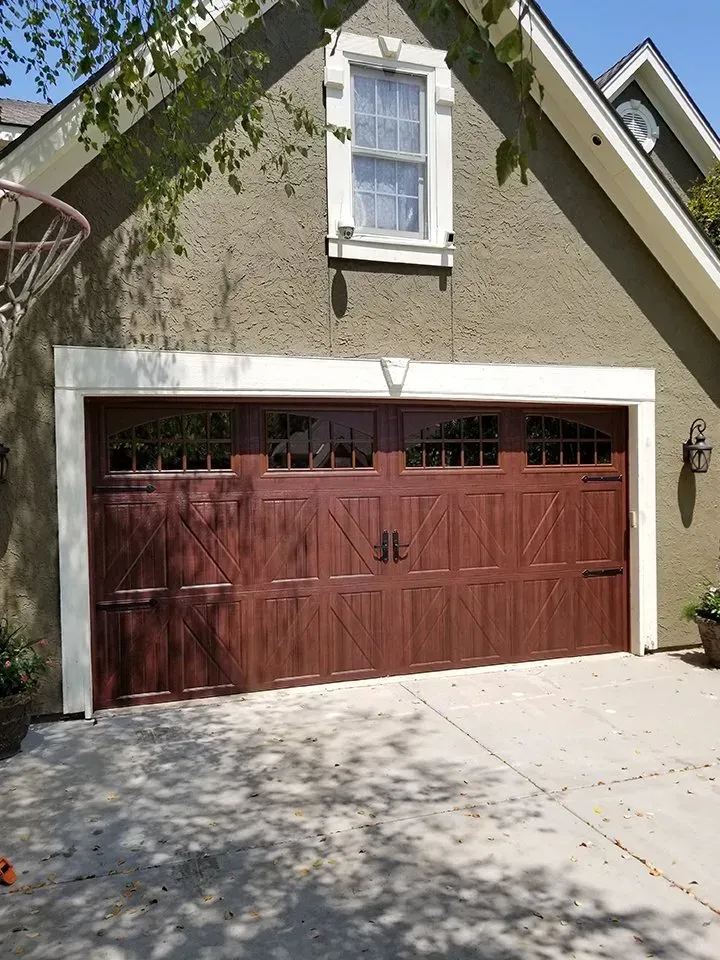 A large brown garage door is on the side of a house