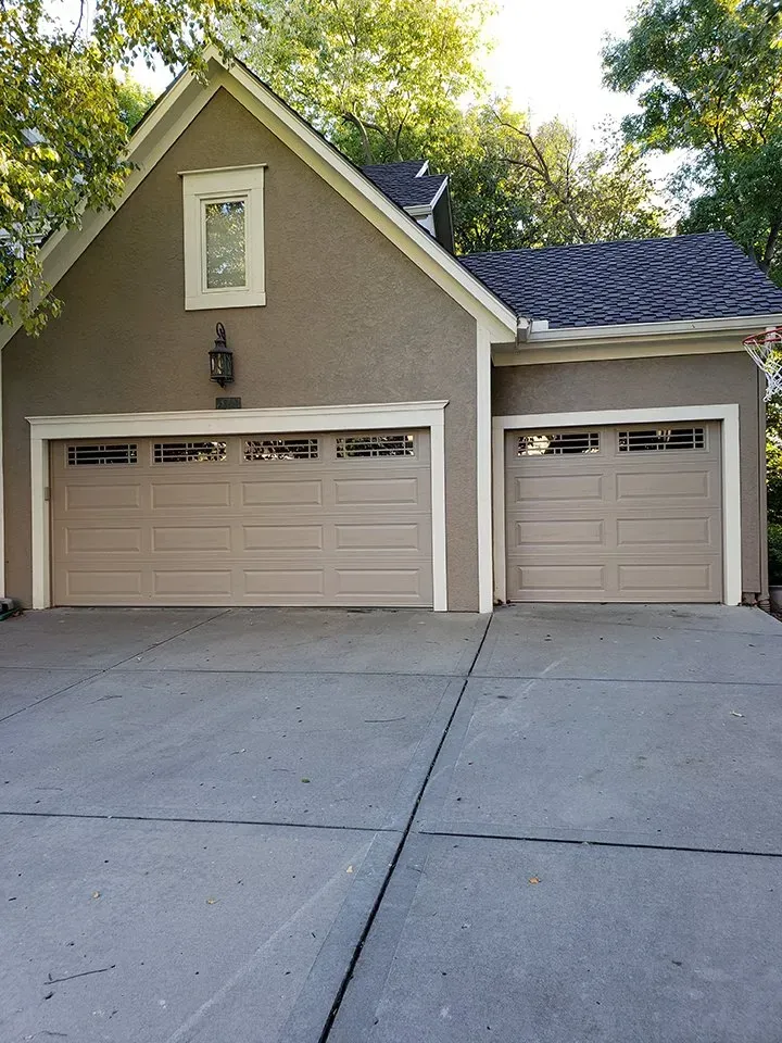 A house with two garage doors and a concrete driveway