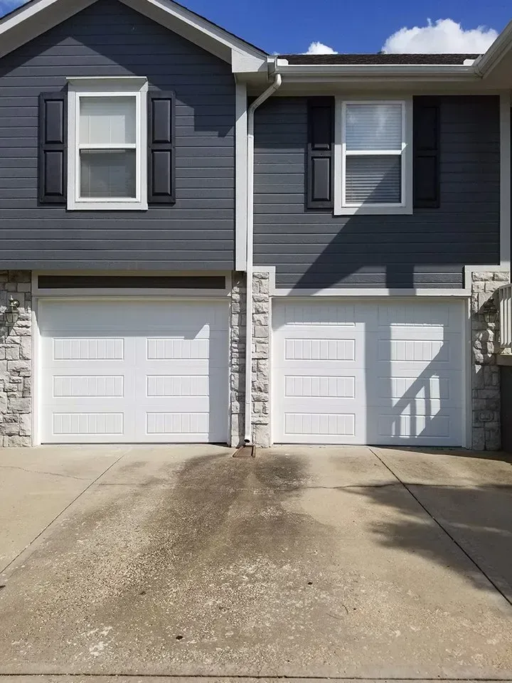 The front of a house with two garage doors and two windows.